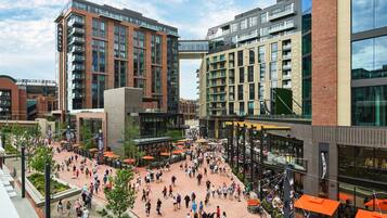 A bustling urban plaza with modern buildings, outdoor seating, and pedestrian pathways.
