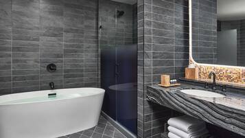 Een moderne badkamer met een vrijstaand bad, een douche met glazen wanden en een wastafel met een backsplash van mozaïektegels.