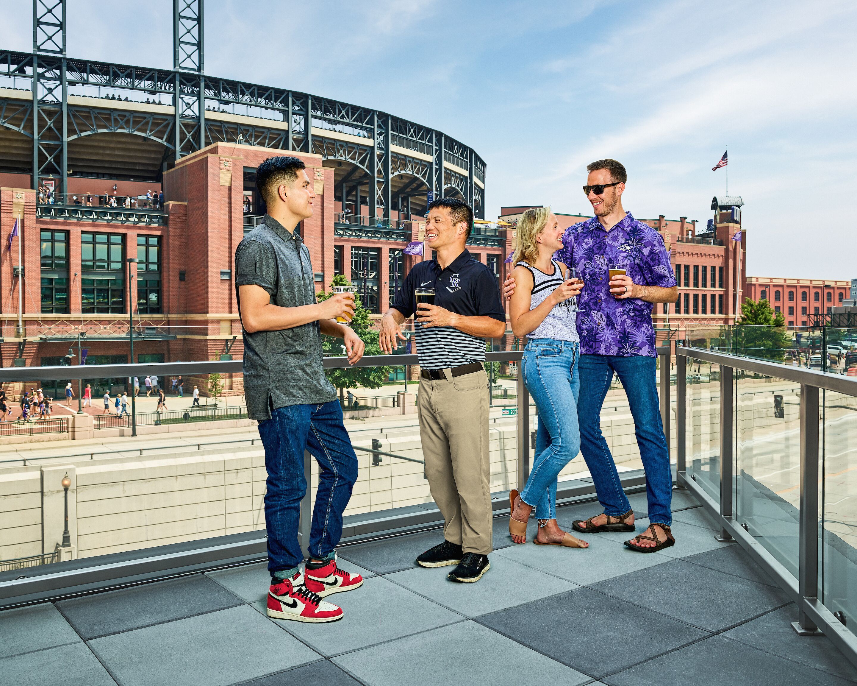 A group of people standing on a balcony with a stadium in the background.