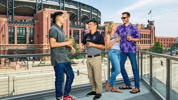 A group of people standing on a balcony with a stadium in the background.