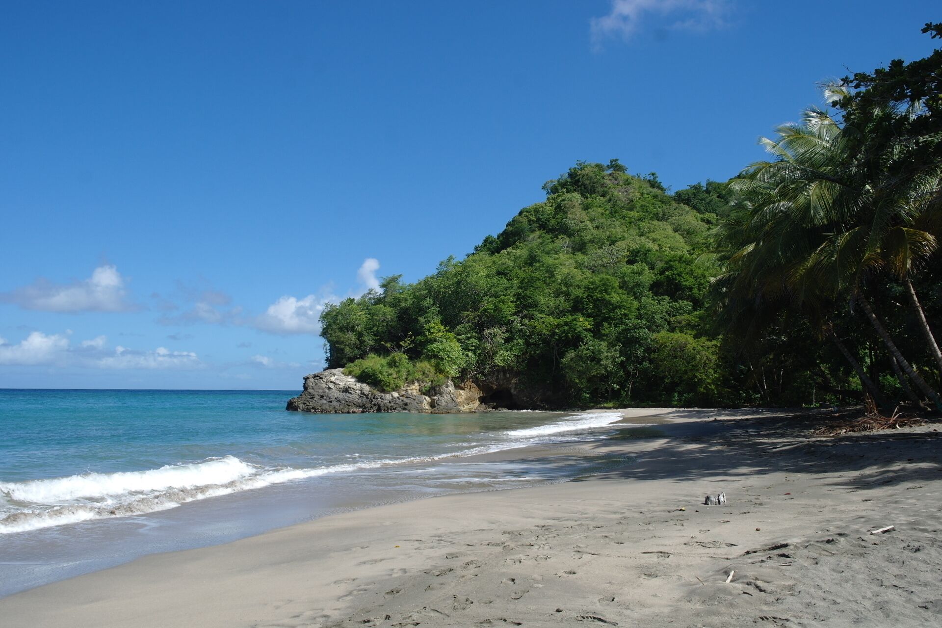 Une plage à l’eau d’un bleu cristallin, bordée d’un rivage sablonneux et d’une végétation luxuriante.
