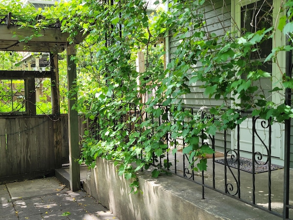A covered outdoor area with a wooden fence, concrete steps, and a metal railing. - Enjoy this amazing home and yard as you eat, pray and fall in love with NE Mpls. (Minneapolis)