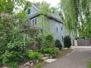 A two-story house with a grey siding exterior, a front porch, and a driveway leading to the entrance. - Enjoy this amazing home and yard as you eat, pray and fall in love with NE Mpls. (Minneapolis)