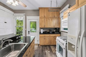 A kitchen with wooden cabinets, a stainless steel sink, a stove, and a refrigerator.