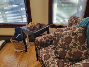 A living room with a chessboard, a patterned sofa, a wicker basket, and wooden flooring. - Enjoy this amazing home and yard as you eat, pray and fall in love with NE Mpls. (Minneapolis)