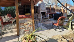 Une terrasse extérieure avec des murs en pierre, un foyer et des sièges d’extérieur.