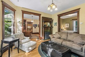 A spacious living room with a fireplace, a dining area, and a large window.