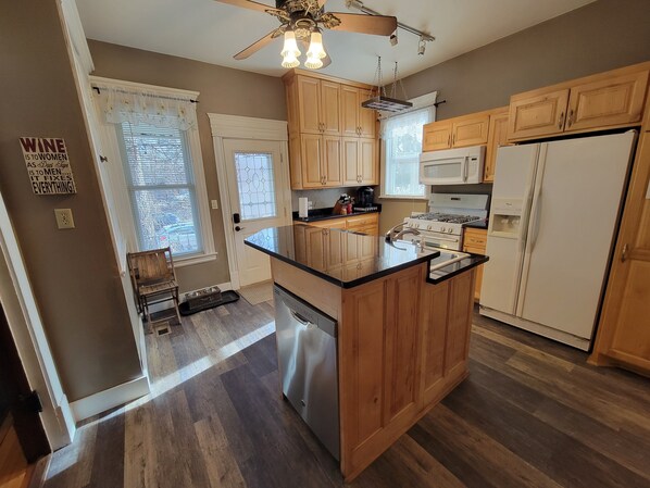 A kitchen with wooden cabinets, a stainless steel dishwasher, a white refrigerator, and a ceiling fan. - Enjoy this amazing home and yard as you eat, pray and fall in love with NE Mpls. (Minneapolis)