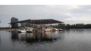 Un grand bâtiment à la structure métallique, entouré d’une étendue d’eau calme et de bateaux.