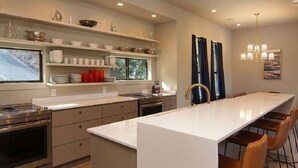 A modern kitchen with a central island, built-in appliances, and a dining area with chairs. - Welcome to Gemstone at Possum Kingdom Lake (Graford)