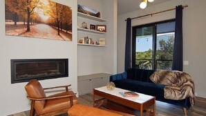 A living room with a fireplace, a sofa, a coffee table, and a bookshelf. - Welcome to Gemstone at Possum Kingdom Lake (Graford)