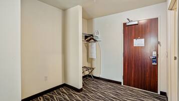 A hallway with a patterned carpet, a wooden door with a sign, and a wall-mounted drying rack.