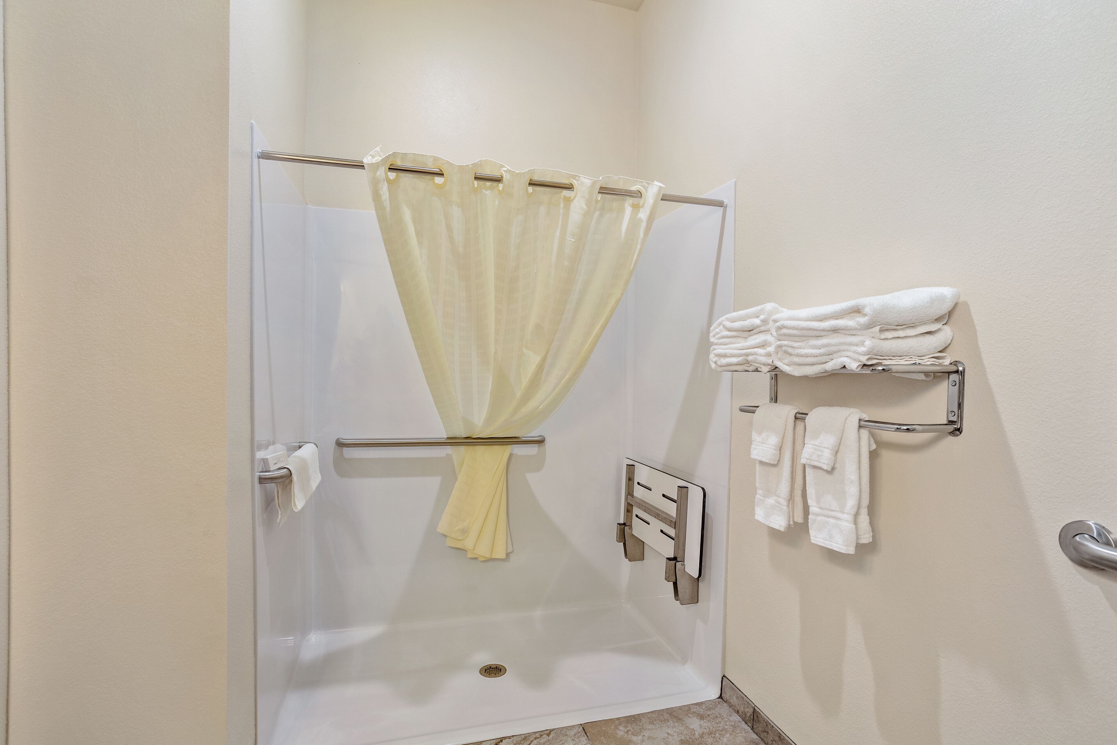 Eine begegnete Dusche mit gelbem Duschvorhang, einem Handtuchhalter mit gefalteten Handtüchern und einem an der Wand montierten Handtuchwärmer.