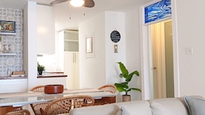 A dining area with a wooden table, wicker chairs, and a potted plant. - Cozy 2 Bdrms Condo Apt Few Steps from the Beach (Río Grande)