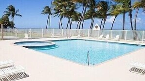 A rectangular swimming pool with a white deck, surrounded by white lounge chairs and a white fence. - Cozy 2 Bdrms Condo Apt Few Steps from the Beach (Río Grande)