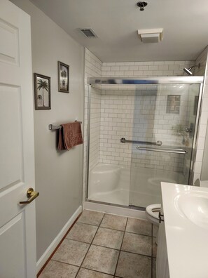 Une salle de bain avec une douche à parois de verre, une baignoire blanche et des toilettes.