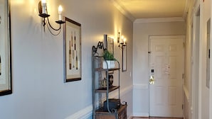 Un couloir doté d’un plancher en bois, d’une porte blanche et d’appliques murales.