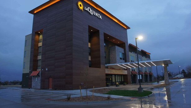 A modern hotel building with a prominent 'La Quinta' sign, large windows, and a covered entrance area.