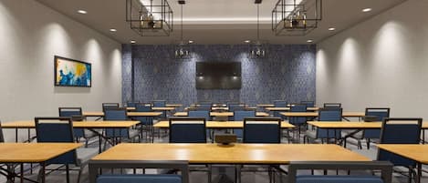 A conference room with multiple tables and chairs, a flat-screen TV, and geometric patterned walls.