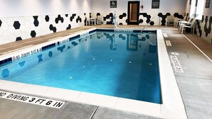 A swimming pool with a no diving sign, hexagonal wall tiles, and a pool lift sign.