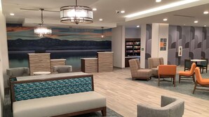 A modern lounge area with a sofa, armchairs, and a round table.
