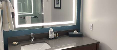 A modern bathroom with a large mirror, a sink, and a towel rack.