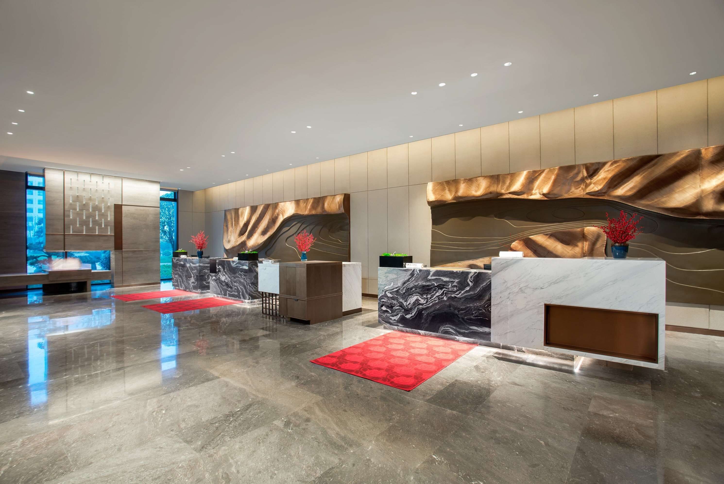 A modern reception area with marble counters, a red patterned rug, and a large wall mural.