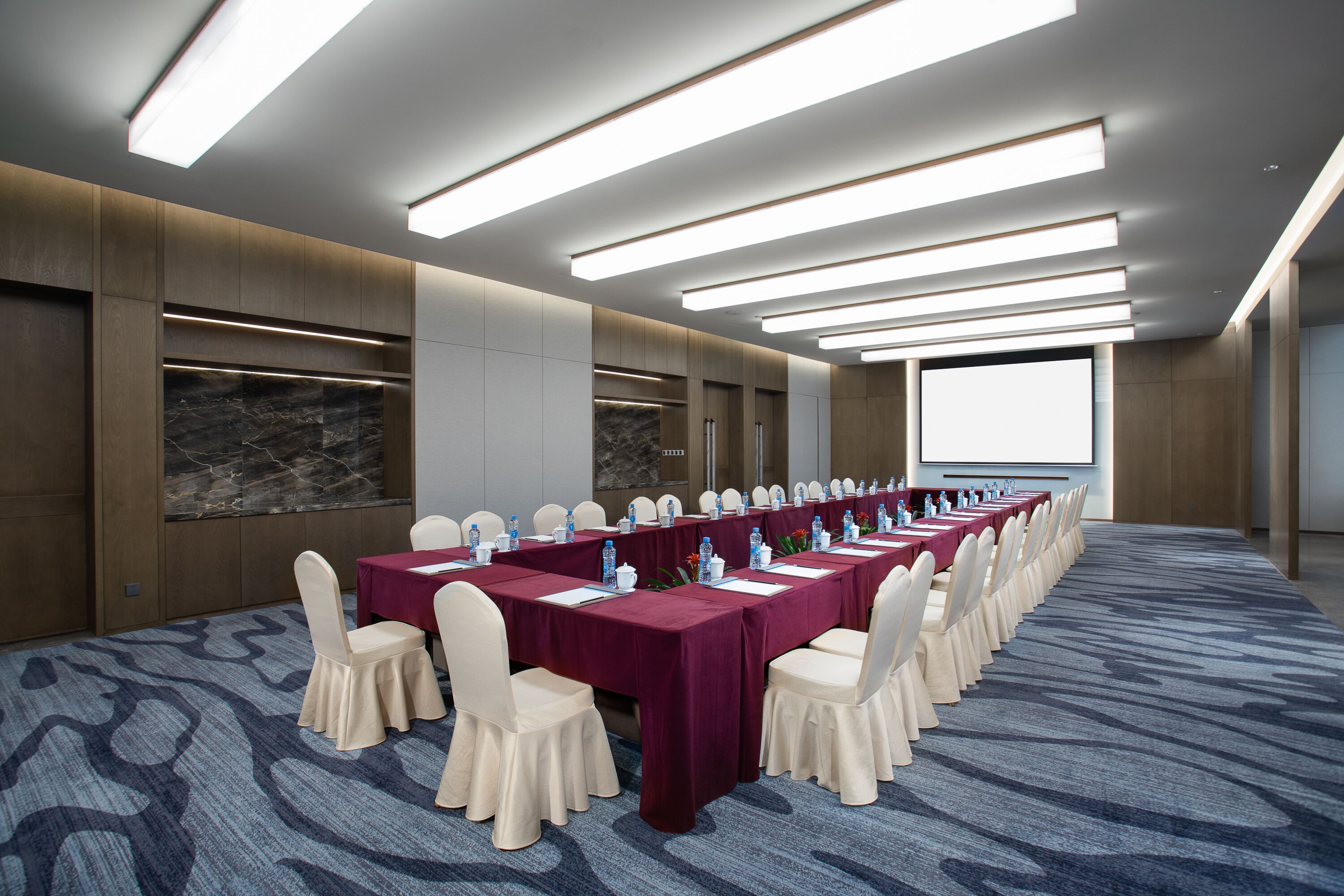 A conference room with a long table, chairs, and a carpeted floor.