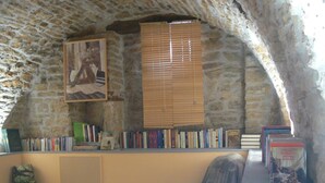 A cozy reading nook with a stone ceiling, a bookshelf filled with books, a comfortable chair, and a small table.