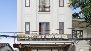 Um edifício branco com uma placa que diz 'TRAVEL HOSTEL' e uma varanda com grades.
