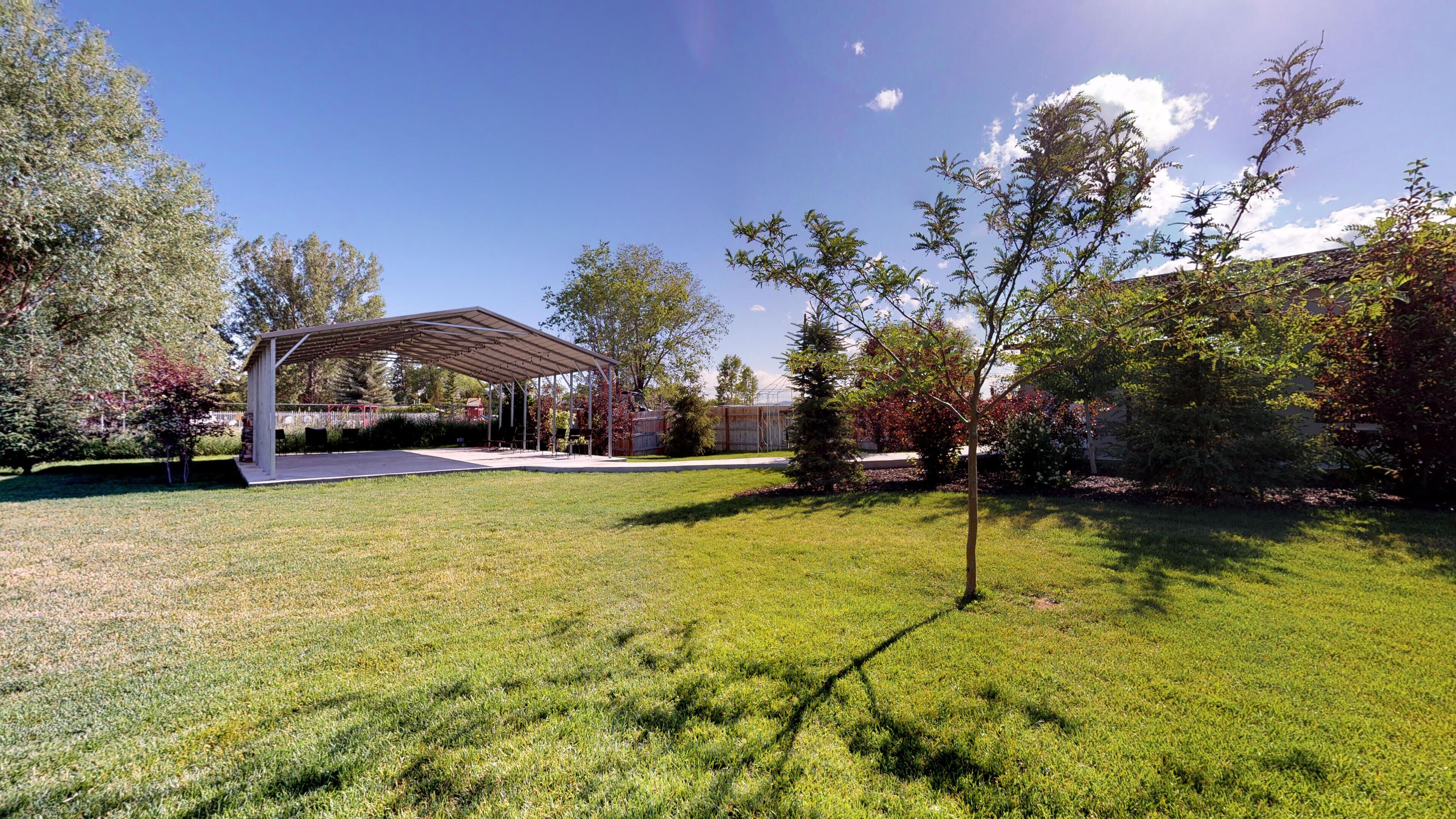 A covered outdoor area with a lawn and trees.