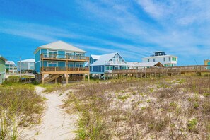 A beachfront property with multiple buildings, a wooden deck, and a sandy path leading to the beach.
