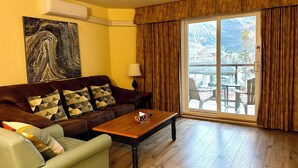A living room with a brown leather sofa, a wooden coffee table, and a large painting on the wall.