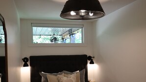 A bedroom with a bed, bedside lamps, a ceiling fan, a window, and a mirror. - L3nee's Lay-Up by Creative Cabins (Logan)