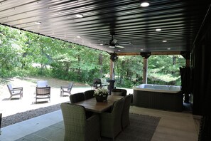 Une terrasse extérieure avec une table, des chaises, un jacuzzi et un espace barbecue.