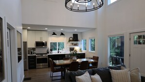 A modern kitchen with a dining area and a living room with a black leather couch. - L3nee's Lay-Up by Creative Cabins (Logan)