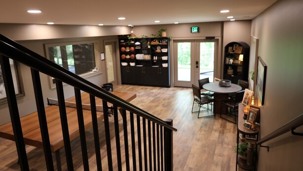A modern interior with a staircase, a dining area, and a kitchen area with shelves. - L3nee's Lay-Up by Creative Cabins (Logan)