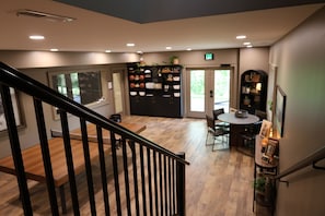 A modern interior with a staircase, a dining area, and a kitchen area with shelves. - L3nee's Lay-Up by Creative Cabins (Logan)