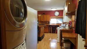 A compact kitchen with wooden cabinets, a sink, a stove, and a clock on the wall.