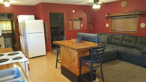 A compact kitchen with a refrigerator, stove, and wooden bar counter.