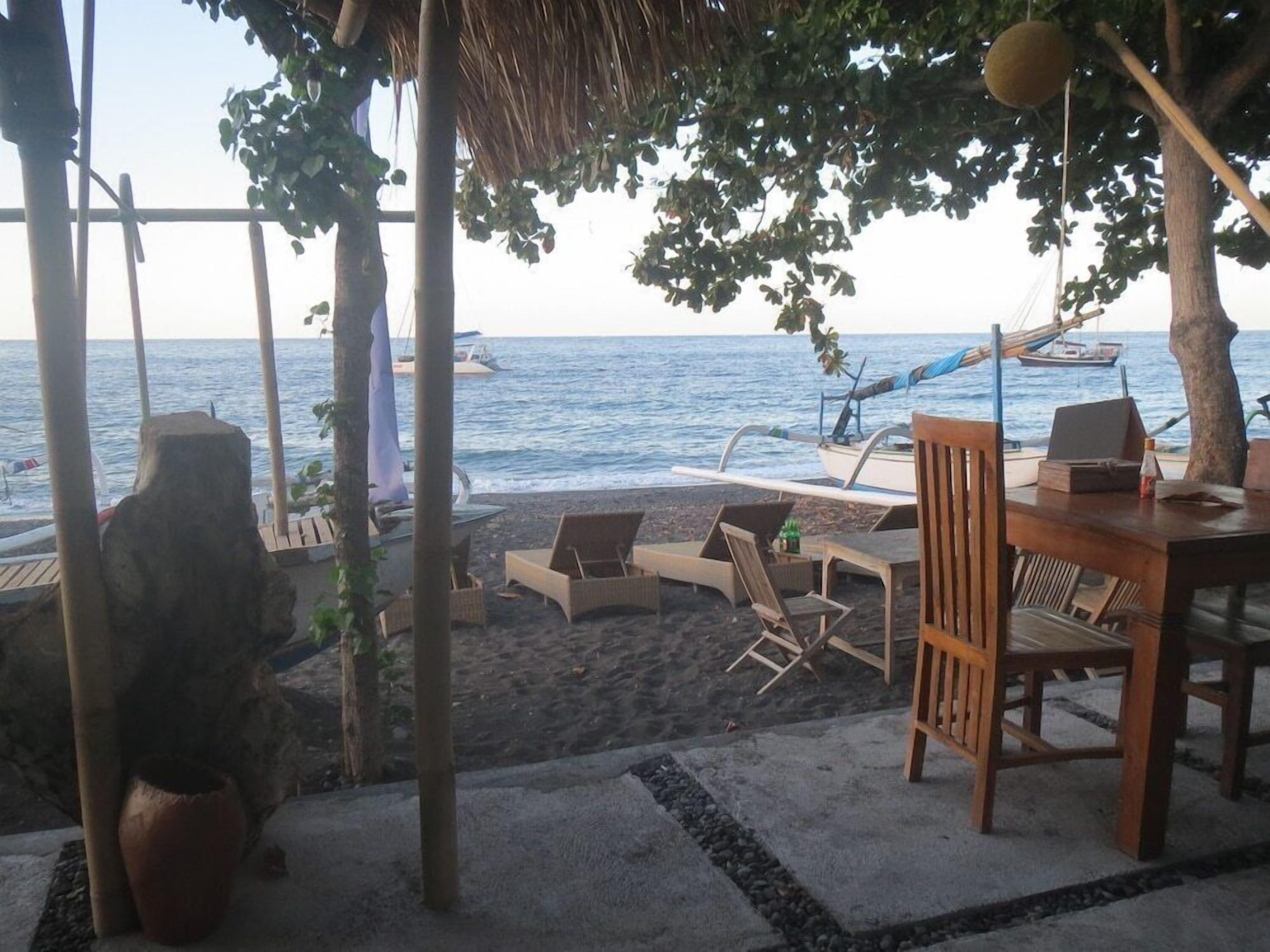 A beachside seating area with lounge chairs and a table, overlooking the sea.