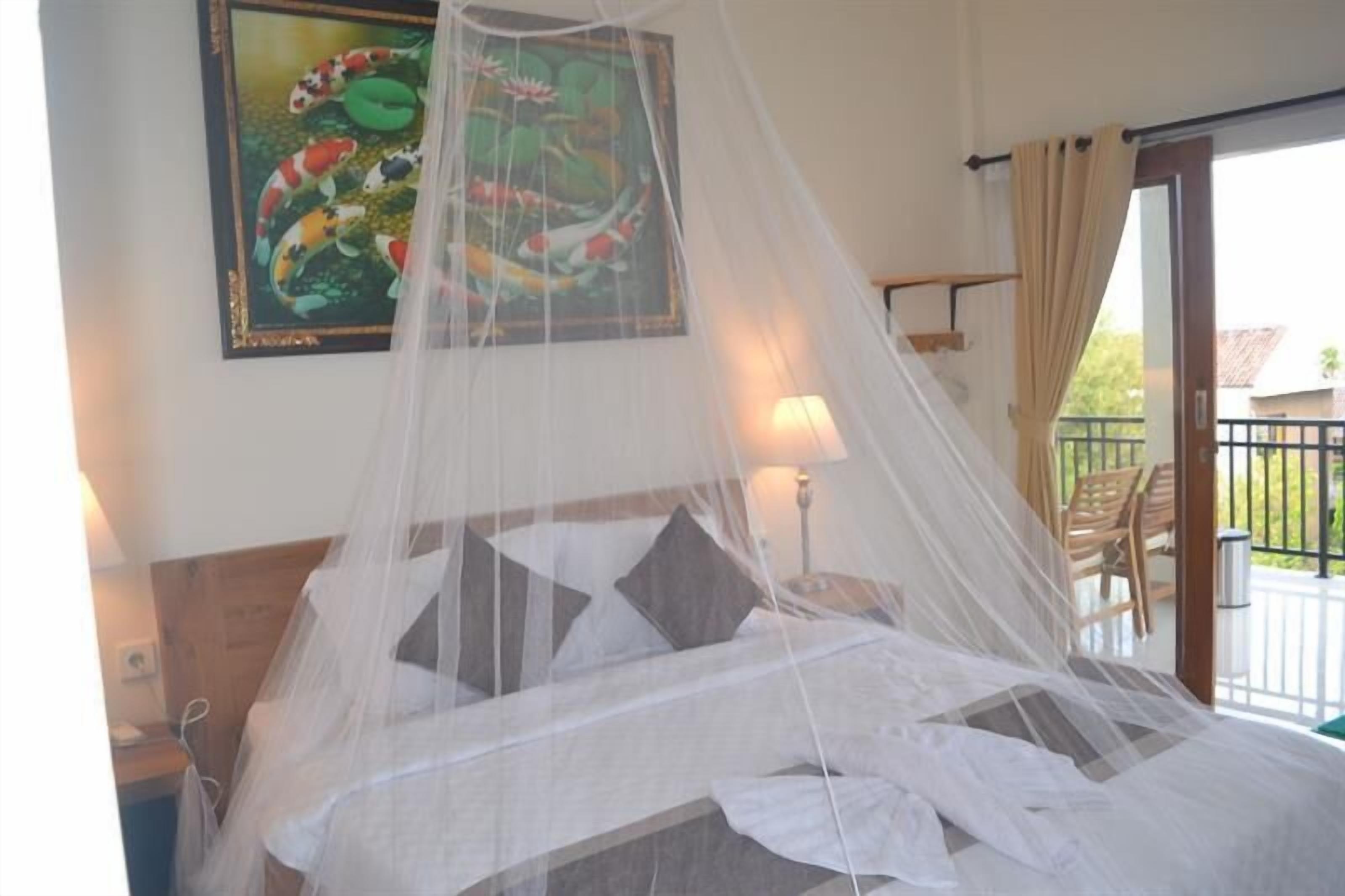 A bed with a mosquito net, a painting of koi fish, and a balcony with chairs.