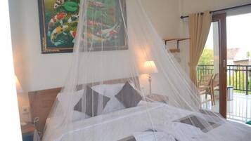 A bed with a mosquito net, a painting of koi fish, and a balcony with chairs.