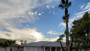 A two-story house with a covered porch, surrounded by palm trees and a clear sky. - Le Beau Soleil (Sun City West)