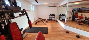 A gym with exercise equipment, a bench, and a rack of dumbbells.
