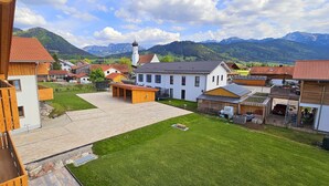 A residential area with a central courtyard, houses with red-tiled roofs, and a church with a bell tower. - Apartment Hipp No. 3 - 90m² new building on the 1st floor with balcony and mountain view in a top location (Halblech)