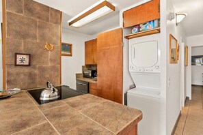 Eine moderne Küche mit Herd, Mikrowelle und Geschirrspüler. Es gibt einen Holzkasten mit einer Mikrowelle obenauf und eine Waschmaschine in der Ecke.