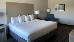 A hotel room with a large bed, a nightstand, a chair, a lamp, and a painting on the wall. - Best Western Plus Chandler (Chandler)