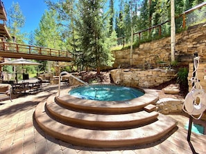 A hot tub with a stone wall and a wooden deck with outdoor furniture. - Timbers 3076 (Keystone)