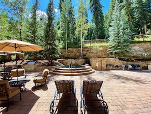 An outdoor patio with a stone wall, a hot tub, and lounge chairs. - Timbers 3076 (Keystone)